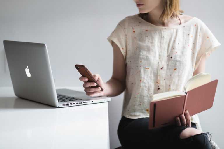 woman multitasking with phone, book and Mac